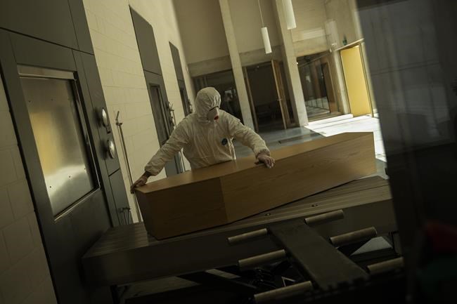 FILE - A worker, wearing full protective gear, moves the casket of a victim of COVID-19 to be cremated during a partial lockdown to prevent the spread of coronavirus at the Pontes crematorium center in Lommel, Belgium, Thursday, April 16, 2020. The World Health Organization is estimating that nearly 15 million people were killed either by the coronavirus or by its impact on overwhelmed health systems in the past two years. That is more than double its official death toll. The U.N. health agency says most of the fatalities were in Southeast Asia, Europe and the Americas. In a report released Thursday, May 5, 2022 WHO chief Tedros Adhanom Ghebreyesus describes the figure as “sobering.