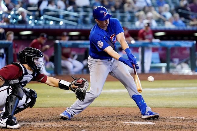 Chicago Cubs' Frank Schwindel, right, connects for a run-scoring single as Arizona Diamondbacks catcher Daulton Varsho reaches out with his glove during the ninth inning of a baseball game Sunday, May 15, 2022, in Phoenix. (AP Photo/Ross D. Franklin)
