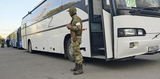 A Russian serviceman guards a bus with Ukrainian servicemen after they were evacuated from the besieged Mariupol's Azovstal steel plant, near a remand prison in Olyonivka, in a territory under the government of the Donetsk People's Republic control, eastern Ukraine, Tuesday, May 17, 2022. More than 260 fighters, some severely wounded, were pulled from a steel plant on Monday that is the last redoubt of Ukrainian fighters in the city and transported to two towns controlled by separatists, officials on both sides said. (AP Photo/Alexei Alexandrov)