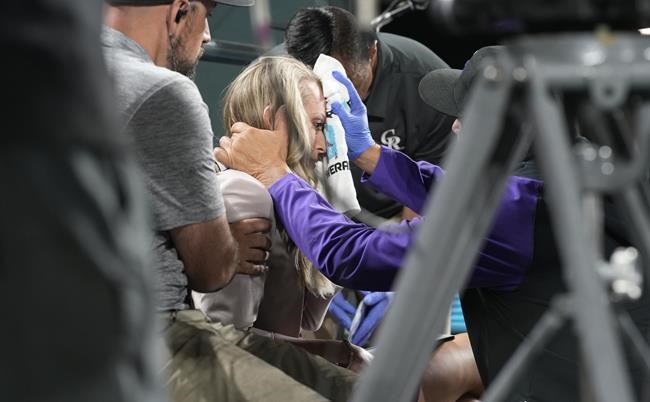 Colorado Rockies television reporter Kelsey Wingert is attended to after being hit by a foul ball off the bat of San Francisco Giants' Austin Slater in the ninth inning of a baseball game Monday, May 16, 2022, in Denver. The announcer, who was seated in the first-base camera well, was taken from the game after being struck in the head by the ball. (AP Photo/David Zalubowski)