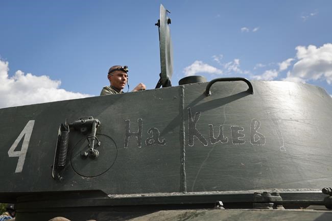 A soldier of Donetsk People's Republic militia sits in a self-propelled artillery vehicle 'Gvozdika' ('Carnation') with writing reading 'towards Kyiv!', near the town of Yasynuvataya, outside Donetsk, in territory under the government of the Donetsk People's Republic, eastern Ukraine, Friday, May 20, 2022. (AP Photo/Alexei Alexandrov)