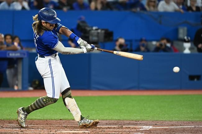 Toronto Blue Jays' Bo Bichette hits an RBI double, scoring George Springer, not shown, in the fifth inning of an Interleague League baseball game against the Cincinnati Reds in Toronto on Friday, May 20, 2022. THE CANADIAN PRESS/Jon Blacker