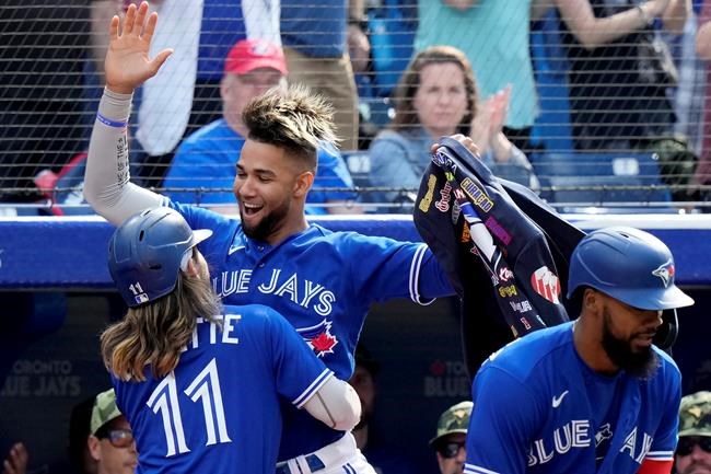 Toronto Blue Jays shortstop Bo Bichette (11) celebrates his two run home run, his second homer of the game, with teammate Lourdes Gurriel Jr. (13) during seventh inning MLB interleague baseball action against the Cincinnati Reds, in Toronto, Saturday, May 21, 2022. THE CANADIAN PRESS/Frank Gunn