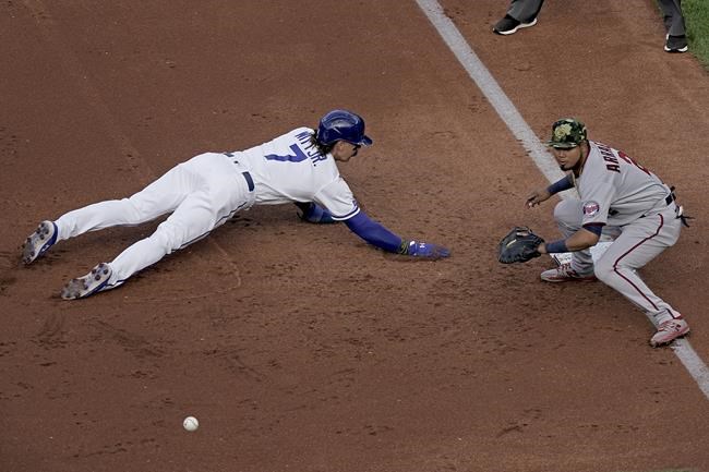 Kansas City Royals' Bobby Witt Jr. (7) beats the tag by Minnesota Twins first baseman Luis Arraez as he dives back to first on a pickoff attempt during the first inning of a baseball game Saturday, May 21, 2022, in Kansas City, Mo. (AP Photo/Charlie Riedel)