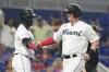 Miami Marlins Garrett Cooper (26), right, is congratulated by Jesus Sanchez after Cooper scored on a hit by Brian Anderson in the sixth inning of a baseball game against the Atlanta Braves, Sunday, May 22, 2022, in Miami. (AP Photo/Marta Lavandier)