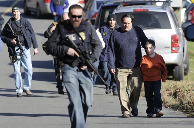 FILE- In this Dec. 14, 2012 file photo, parents leave a staging area after being reunited with their children following a shooting at the Sandy Hook Elementary School in Newtown, Conn. At least 14 children and a teacher were killed in a shooting at a Texas elementary school Tuesday, May 24, 2022, Texas Gov. Greg Abbott said. (AP Photo/Jessica Hill, File)
