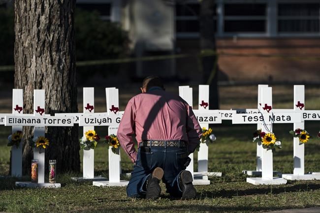 Pastor Daniel Myers kneels in front of crosses bearing the names of Tuesday's shooting victims while praying for them at Robb Elementary School in Uvalde, Texas, Thursday, May 26, 2022. (AP Photo/Jae C. Hong)
