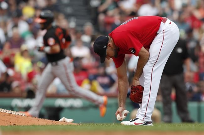Boston Red Sox's Nathan Eovaldi reaches for the rosin bag after giving up a two-run home run to Baltimore Orioles' Robinson Chirinos, left, during the fifth inning of the first game of a baseball doubleheader, Saturday, May 28, 2022, in Boston. (AP Photo/Michael Dwyer)