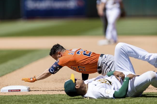 Houston Astros' Jose Altuve, top, reaches back to touch first base after colliding with Oakland Athletics first baseman Christian Bethancourt, bottom, during the seventh inning of a baseball game in Oakland, Calif., Monday, May 30, 2022. (AP Photo/John Hefti)