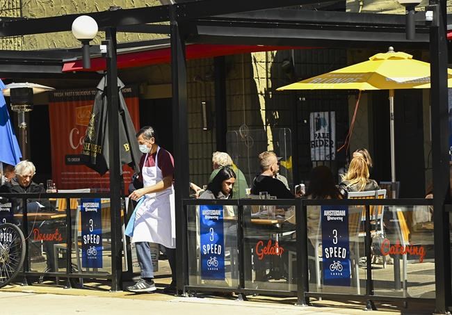 People sit on the outdoor patio at a restaurant in Little Italy during the COVID-19 pandemic in Toronto on Tuesday, March 30, 2021. Statistics Canada says restaurant and bar sales in March 2022 surpassed pre-pandemic levels. THE CANADIAN PRESS/Nathan Denette