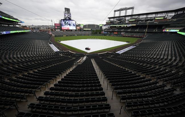 A tarpulin covers the diamond of Coors Field after a baseball game between the Miami Marlins and Colorado Rockies was postponed by stormy weather Tuesday, May 31, 2022, in Denver. The game will be made up as part of a doubleheader on Wednesday, June 1. (AP Photo/David Zalubowski)