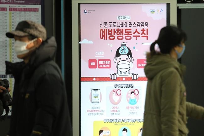 People pass by a poster warming about a new coronavirus at Suseo Station in Seoul, South Korea, Friday, Jan. 24, 2020. China broadened its unprecedented, open-ended lockdowns to encompass around 25 million people Friday to try to contain a deadly new virus that has sickened hundreds, though the measures' potential for success is uncertain. The sign reads