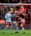 Aston Villa's Frederic Guilbert appears to get kicked in the head by Sheffield United's Oliver McBurnie as he challenges for the ball, during the English Premier League soccer match between Sheffield United and Aston Villa, at Bramall Lane, in Sheffield, England, Saturday, Dec. 14, 2019. (Mike Egerton/PA via AP)