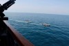 In this Wednesday, April 15, 2020, photo made available by U.S. Navy, Iranian Revolutionary Guard vessels sail close to U.S. military ships in the Persian Gulf near Kuwait. A group of 11 Iranian naval vessels made 