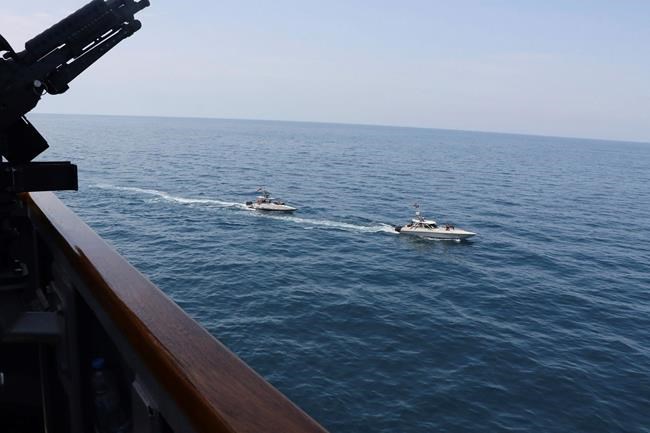 In this Wednesday, April 15, 2020, photo made available by U.S. Navy, Iranian Revolutionary Guard vessels sail close to U.S. military ships in the Persian Gulf near Kuwait. A group of 11 Iranian naval vessels made