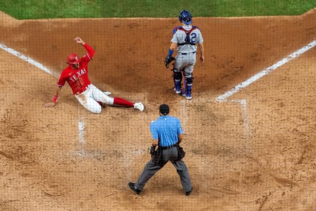Texas Rangers' Ronald Guzman, left, slides safely in front of Los Angeles Dodgers catcher Austin Barnes, top right, and home plate umpire Adam Mamari on a sacrifice fly by Shin-Soo Choo during the fifth inning of a baseball game Saturday, Aug. 29, 2020, in Arlington, Texas. (AP Photo/Jeffrey McWhorter)