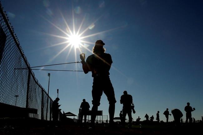 San Diego Padres pitcher Chris Paddack uses an elastic rope to stretch during baseball spring training Thursday, Feb. 13, 2020, in Peoria, Ariz. (AP Photo/Charlie Riedel)