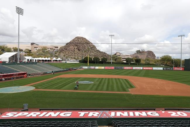 A grounds crew member applies fertilizer to the field as players report for spring training baseball, Tuesday, Feb. 11, 2020, in Tempe, Ariz. Los Angeles Angels pitchers and catchers start practice on Wednesday. (AP Photo/Darron Cummings)