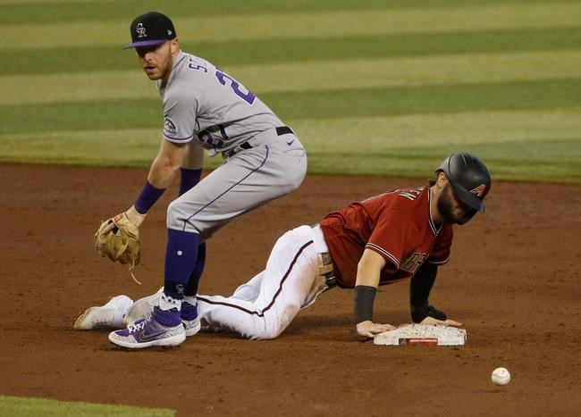 Colorado Rockies shortstop Trevor Story, left, looks for the ball after Arizona Diamondbacks' Wyatt Mathisen dove back into second base during the fourth inning of a baseball game Sunday, Sept. 27, 2020, in Phoenix. (AP Photo/Darryl Webb)