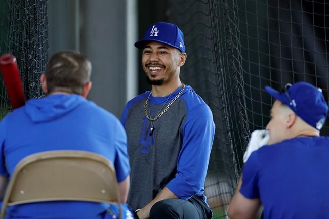 Los Angeles Dodgers outfielder Mookie Betts, center, talks with second baseman Max Muncy, left, and right fielder Joc Pederson, right, during spring training baseball Monday, Feb. 17, 2020, in Phoenix. (AP Photo/Gregory Bull)