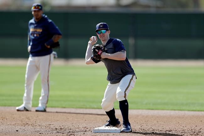 Milwaukee Brewers infielder Brock Holt throws to first as shortstop Orlando Arcia looks on, left, during spring training baseball Wednesday, Feb. 19, 2020, in Phoenix. Holt and the Brewers finalized a one-year contract Wednesday, a deal that includes a team option for 2021. (AP Photo/Gregory Bull)