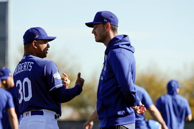 Los Angeles Dodgers manager Dave Roberts, left, talks with center fielder Cody Bellinger during spring training baseball Friday, Feb. 14, 2020, in Phoenix. (AP Photo/Gregory Bull)
