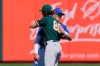 Kansas City Royals' Bobby Witt Jr., right, embraces Oakland Athletics' Cody Thomas (80) before a spring training baseball game Monday, March 8, 2021, in Surprise, Ariz. (AP Photo/Sue Ogrocki)