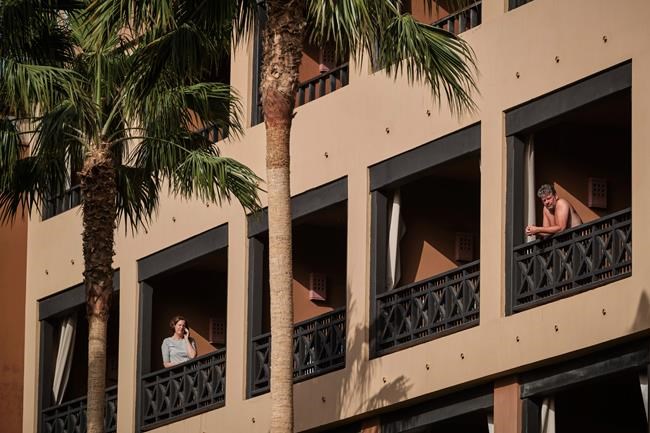 People stand on their balconies of the H10 Costa Adeje Palace hotel in La Caleta, in the Canary Island of Tenerife, Spain, Wednesday, Feb. 26, 2020. Spanish officials say a tourist hotel on the Canary Island of Tenerife has been placed in quarantine after an Italian doctor staying there tested positive for the COVID-19 virus and Spanish news media says some 1,000 tourists staying at the complex are not allowed to leave. (AP Photo)