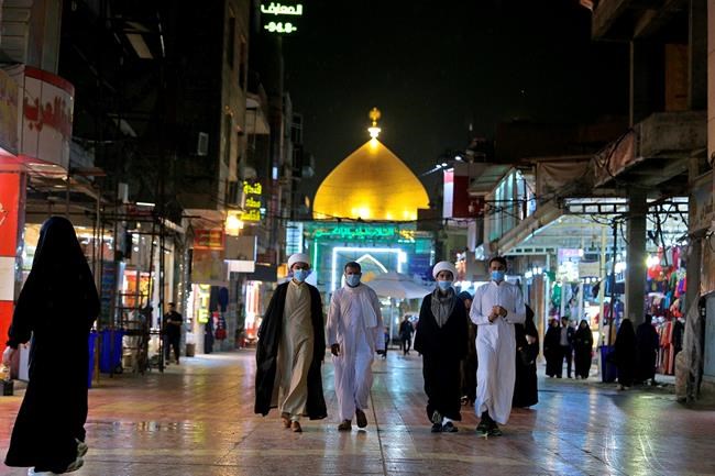 In this Monday, Feb. 24, 2020 photo, Shiite pilgrims wear masks outside the shrine of Imam Ali in Najaf, Iraq. The Health Ministry said four new cases of coronavirus were diagnosed in the northern province of Kirkuk. It said the afflicted were members of an Iraqi family who had returned from a recent trip to Iran. Iraq announced the discovery of the first coronavirus case in the country on Monday in Najaf. Iraq had earlier closed its border with Iran to Iranian nationals but apparently Iraqis can still cross the boundary. (AP Photo/Anmar Khalil)