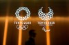 FILE - In this June 11, 2019, file photo, a man walks past the Tokyo 2020 Olympic logos in Tokyo. One of the creative directors for this year's Tokyo Olympics has resigned following allegations of what are being termed “power harassment.” Kaoru Sugano stepped away from the position and his resignation has been confirmed by the Tokyo organizing committee. (AP Photo/Jae C. Hong, File)