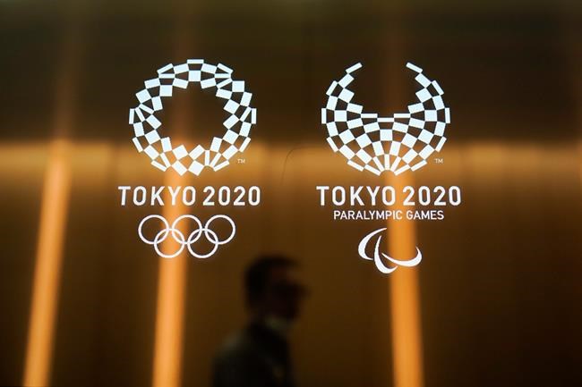 FILE - In this June 11, 2019, file photo, a man walks past the Tokyo 2020 Olympic logos in Tokyo. One of the creative directors for this year's Tokyo Olympics has resigned following allegations of what are being termed “power harassment.” Kaoru Sugano stepped away from the position and his resignation has been confirmed by the Tokyo organizing committee. (AP Photo/Jae C. Hong, File)