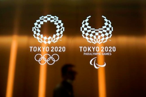 FILE - In this June 11, 2019, file photo, a man walks past the Tokyo 2020 Olympic logos in Tokyo. One of the creative directors for this year's Tokyo Olympics has resigned following allegations of what are being termed “power harassment.” Kaoru Sugano stepped away from the position and his resignation has been confirmed by the Tokyo organizing committee. (AP Photo/Jae C. Hong, File)