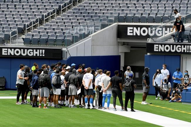 Los Angeles Chargers head coach Anthony Lynn, with players behind him, talks to the media about the cancelation of practice and a scrimmage at SoFi Stadium in Inglewood, Calif., Thursday, Aug. 27, 2020. The team canceled practice due to the recent shooting of Jacob Blake. Lynn canceled practice after his players held a wide-ranging conversation in the locker room spurred by the shooting of Blake, a Black man, in Wisconsin last weekend. (Hans Gutknecht/The Orange County Register via AP)