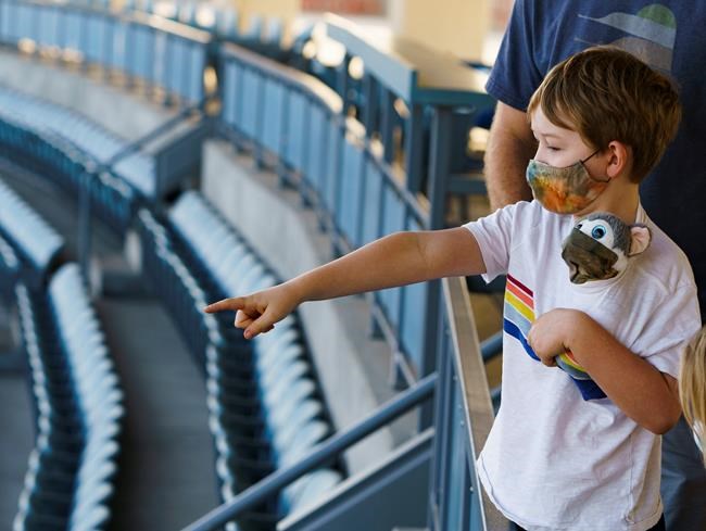 Voters Brandon Malmberg explains the rules of baseball to his son his son, Ashton Malmberg, 7, holding a masked stuffed toy, after his parents voted in-person on Election Day at Dodger Stadium in Los Angeles, Tuesday, Nov. 3, 2020. (AP Photo/Damian Dovarganes)