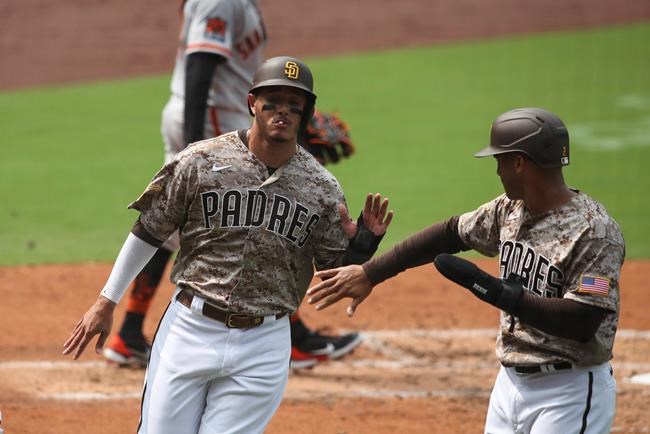 San Diego Padres third baseman Manny Machado high fives Trent Grisham after they score on a single to left field hit by Will Myers against the San Francisco Giants in the third inning of a baseball game Sunday, Sept. 13, 2020, in San Diego. (AP Photo/Derrick Tuskan)