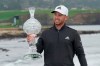 Daniel Berger holds up his trophy on the 18th green of the Pebble Beach Golf Links after winning the AT&T Pebble Beach Pro-Am golf tournament Sunday, Feb. 14, 2021, in Pebble Beach, Calif. (AP Photo/Eric Risberg)