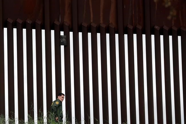 A border patrol agent walks along a border wall separating Tijuana, Mexico, from San Diego, Wednesday, March 18, 2020, in San Diego. (AP Photo/Gregory Bull)