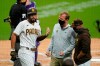 San Diego Padres' Eric Hosmer, left, reacts after injuring his hand while batting during the first inning of a baseball game against the Colorado Rockies Monday, Sept. 7, 2020, in San Diego. Padres manager Jayce Tingler, right, looks on alongside a trainer. (AP Photo/Gregory Bull)