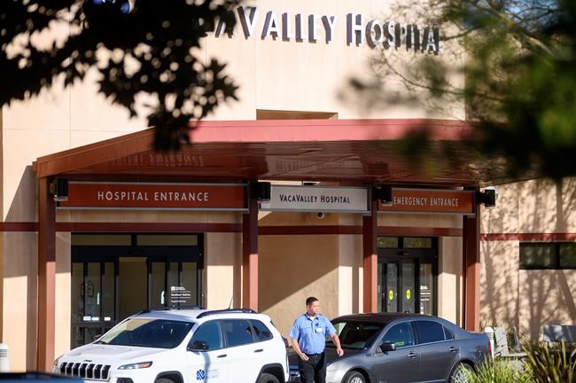 A security guard leaves NorthBay VacaValley Hospital, where a woman diagnosed with coronavirus previously sought treatment, on Thursday, Feb. 27, 2020, in Vacaville, Calif. Public health officials are retracing the steps of the woman, believed to be the first person in the U.S. to contract the highly contagious coronavirus without traveling abroad or coming in close contact with an international traveller. (AP Photo/Noah Berger)