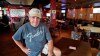 Mike Miller, owner of Wilbert's Food & Music, poses in an almost empty restaurant before a baseball game between the Minnesota Twins and the Cleveland Indians, Tuesday, Aug. 25, 2020, in Cleveland. The coronavirus pandemic has been especially hard on businesses that rely on ballpark traffic, eliminating crowds at major league games, and leading to rules that limit the amount of people they can have inside their doors at the same time.(AP Photo/Tony Dejak)