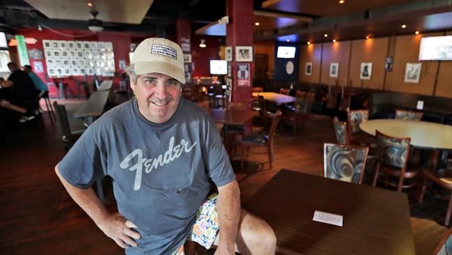 Mike Miller, owner of Wilbert's Food & Music, poses in an almost empty restaurant before a baseball game between the Minnesota Twins and the Cleveland Indians, Tuesday, Aug. 25, 2020, in Cleveland. The coronavirus pandemic has been especially hard on businesses that rely on ballpark traffic, eliminating crowds at major league games, and leading to rules that limit the amount of people they can have inside their doors at the same time.(AP Photo/Tony Dejak)
