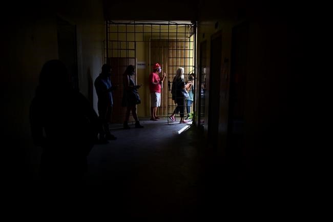 People wait in line to vote in the general election at a polling center set up at the Rafael Labra School in San Juan, Puerto Rico, Tuesday, Nov. 3, 2020. In addition to electing a governor, Puerto Ricans are voting in a non-binding referendum on statehood. (AP Photo/Carlos Giusti)