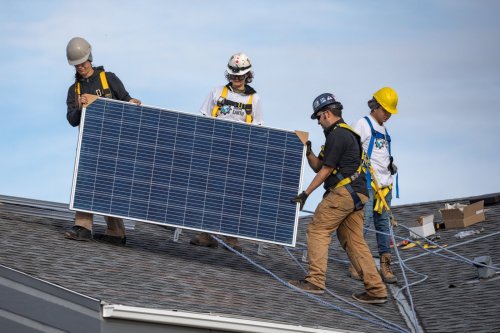 Workers wearing Iron & Earth clothing set up solar panels. (Photo courtesy of Iron & Earth / Facebook)