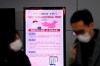 FILE - In this Monday, Jan. 27, 2020, file photo, a poster warning about coronavirus is seen as passengers wear masks in a departure lobby at Incheon International Airport in Incheon, South Korea. British Airways and Asian budget carriers Lion Air and Seoul Air are suspending all flights to China as fears spread about the outbreak of a new virus that has killed more than 130 people. British Airways said Wednesday it is immediately suspending all flights to and from mainland China after the U.K. government warned against unnecessary travel to the country. (AP Photo/Ahn Young-joon, File)