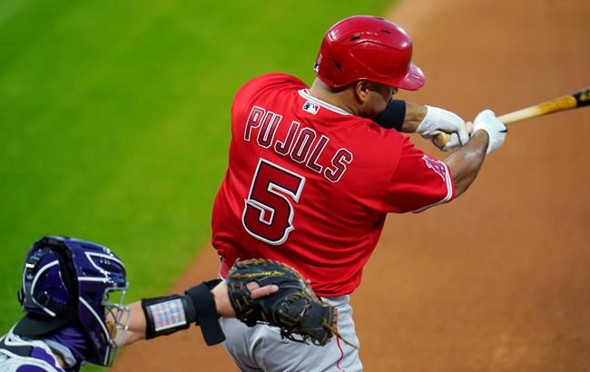 Los Angeles Angels' Albert Pujols, right, connects for a single as Colorado Rockies catcher Tony Wolters looks for the pitch in the fourth inning of a baseball game Saturday, Sept. 12, 2020, in Denver. (AP Photo/David Zalubowski)