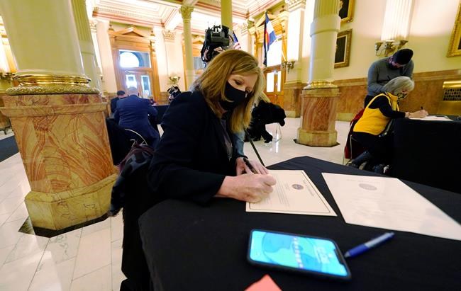 Susan McFaddin, of Fort Collins, Colo., one of Colorado's nine Democratic presidential electors, casts vote for Joe Biden at the State Capitol, Monday, Dec. 14, 2020, in downtown Denver. (AP Photo/David Zalubowski, Pool)