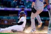 Colorado Rockies' Charlie Blackmon, left, scores on a wild pitch thrown by Los Angeles Dodgers starting pitcher Jimmy Nelson in the seventh inning of a baseball game Thursday, April 1, 2021, in Denver. (AP Photo/David Zalubowski)