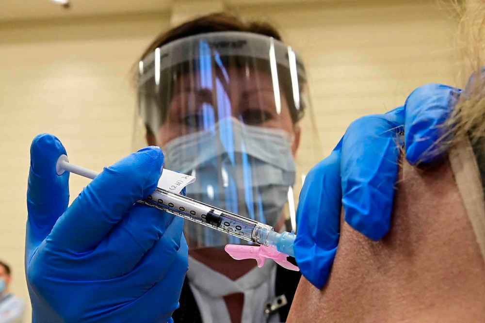 Tamara Dus, director of University Health Network Safety Services, administers a Pfizer-BioNTech COVID-19 vaccine in Toronto on Monday, Dec. 14, 2020. THE CANADIAN PRESS/Frank Gunn