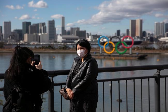 A tourist wearing a mask pauses for photos with the Olympic rings in the background in the Odaiba district of Tokyo, Wednesday, Jan. 29, 2020. THE CANADIAN PRESS/AP-Jae C. Hong