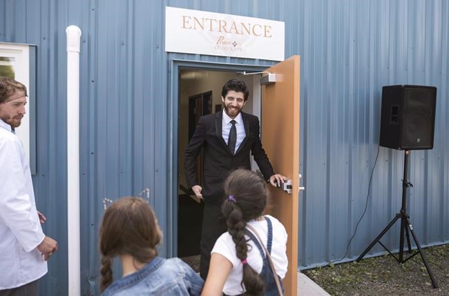 Syrian chocolatier Tareq Hadhad greets children at the door of Peace By Chocolate's newly-opened factory in Antigonish, N.S. on Saturday, September 9, 2017. A Nova Scotia chocolate maker who came to Canada as a Syrian refugee has become a Canadian citizen. Tareq Hadhad, the founder of Peace by Chocolate in Antigonish, took part in a citizenship ceremony today at Pier 21 in Halifax. THE CANADIAN PRESS/Darren Calabrese